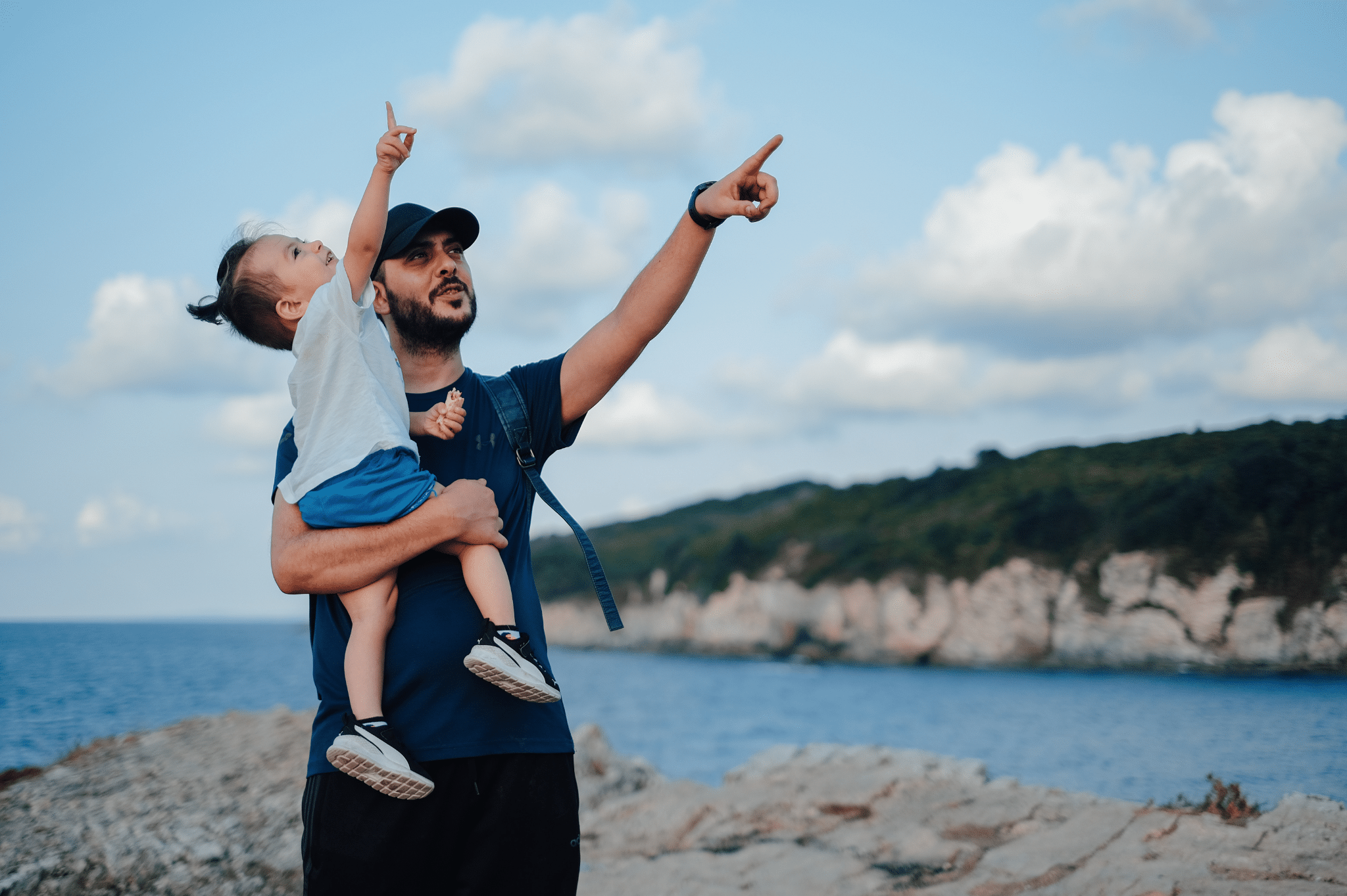 Parent holding a child and pointing at the sky