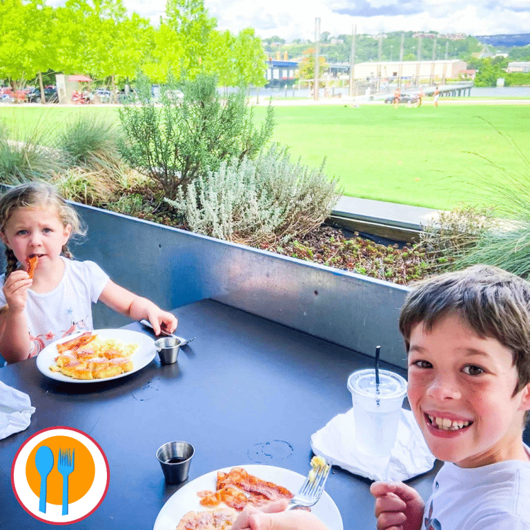 two children smiling and eating a family friendly restaurant