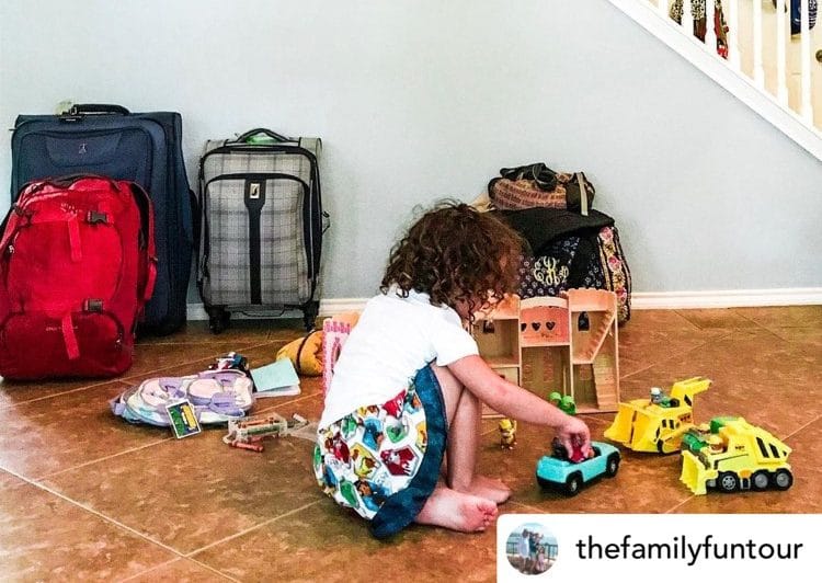 Little girl playing in front of a couple of luggage. Family travel tip pack light.. Source: Thefamilyfuntour.