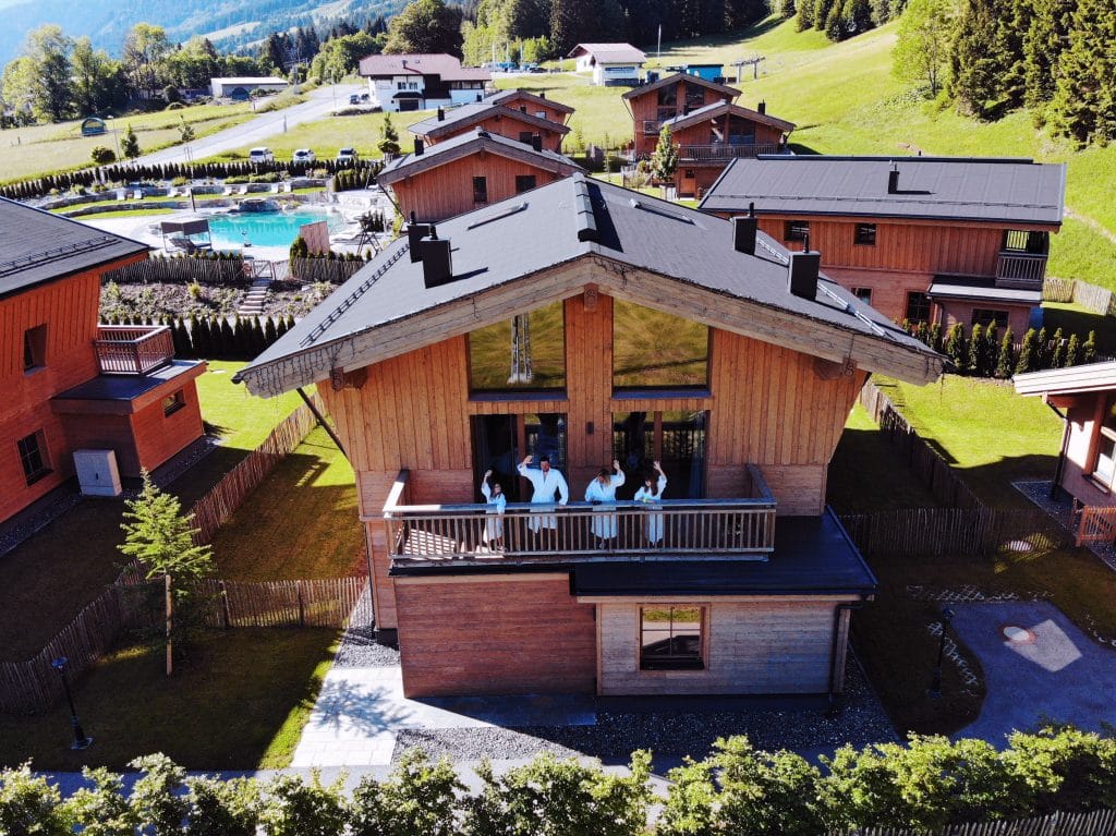 La S.O.A Chalets ski resort in Austria, family waving from the chalet balcony.