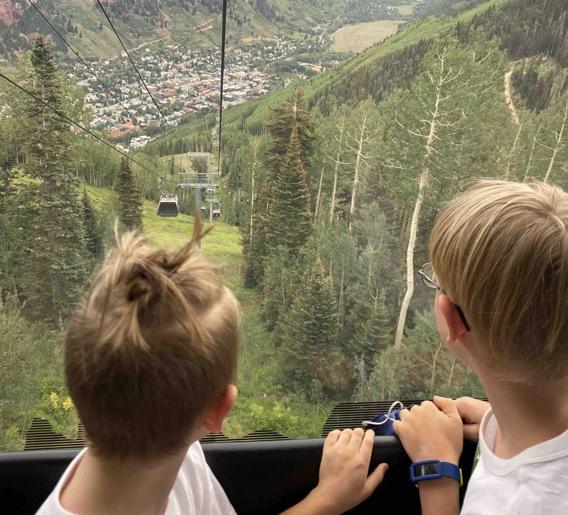 2 Boys looking down from the Telluride gondola . things to do in Colorado with kids blog cover