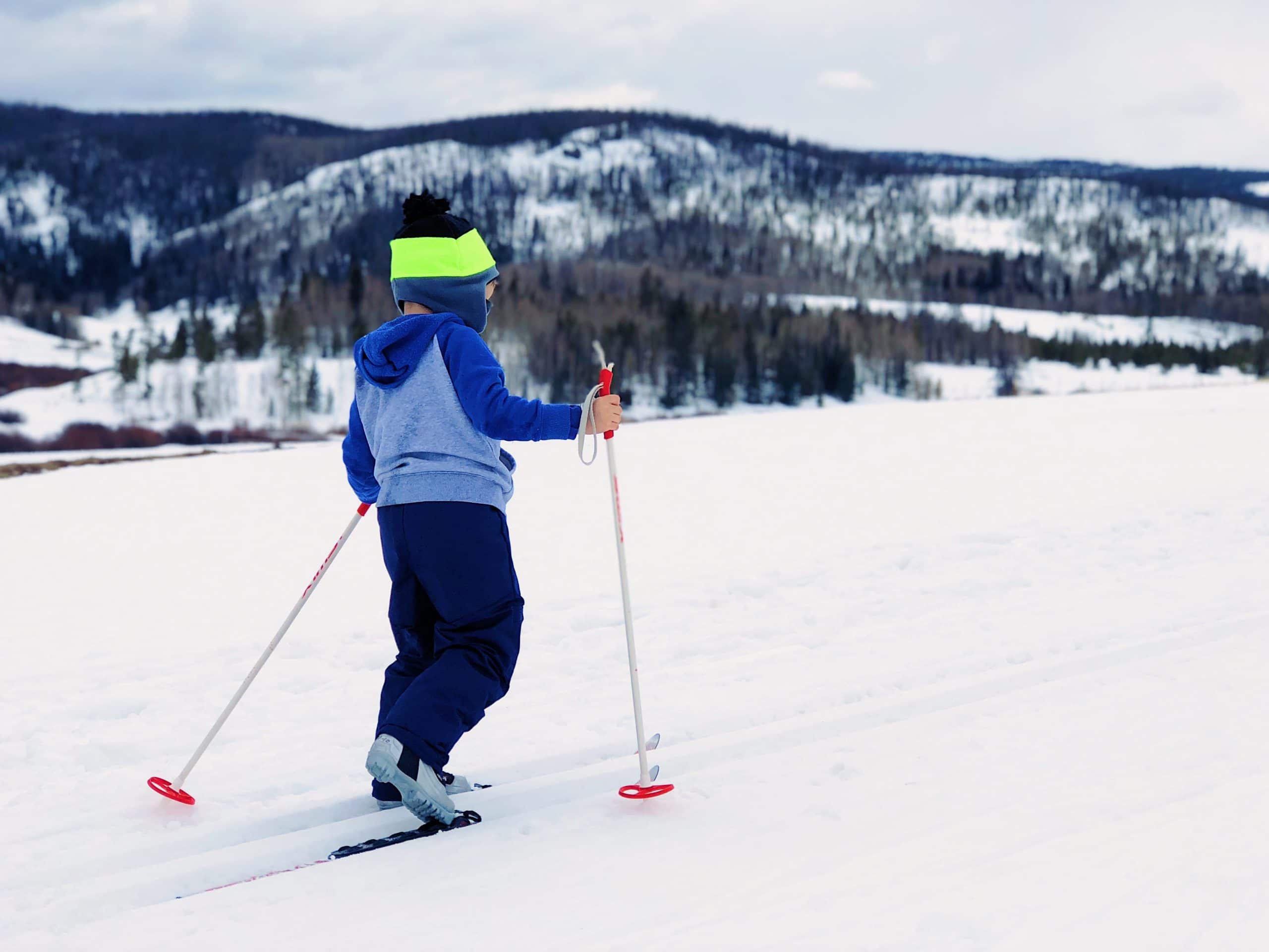 Kid skiing. family winter vacation packing list cover photo