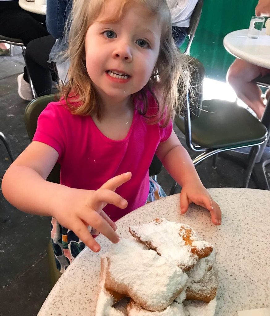 Child eating a beignet at CAfe du monde in New orleans