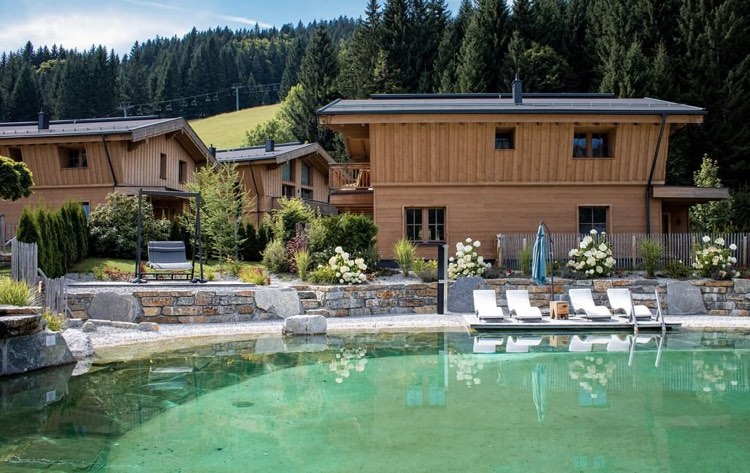 View of the pool and chalets in La S.O.A chalet resort, Austria