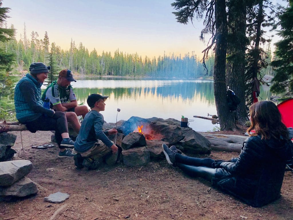 family around campfire by the lake