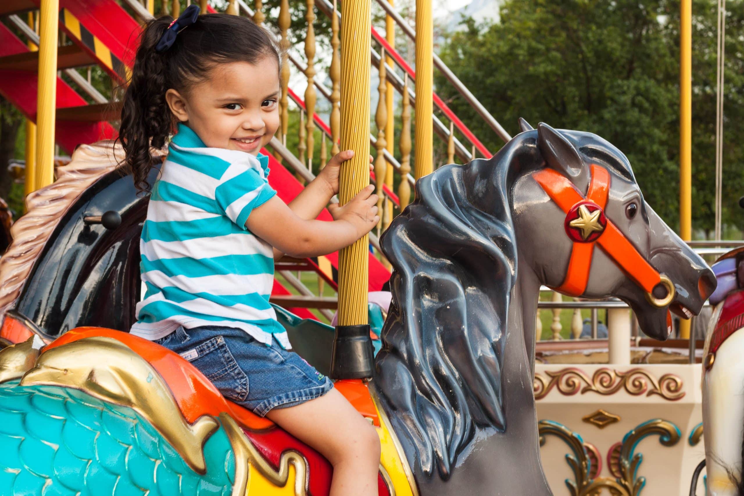 photo of little girl sitting on carrousel horse. alternatives to disney world feature