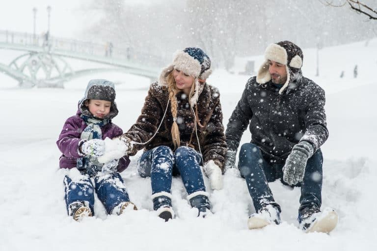 Man, woman, and child sitting in the snow
