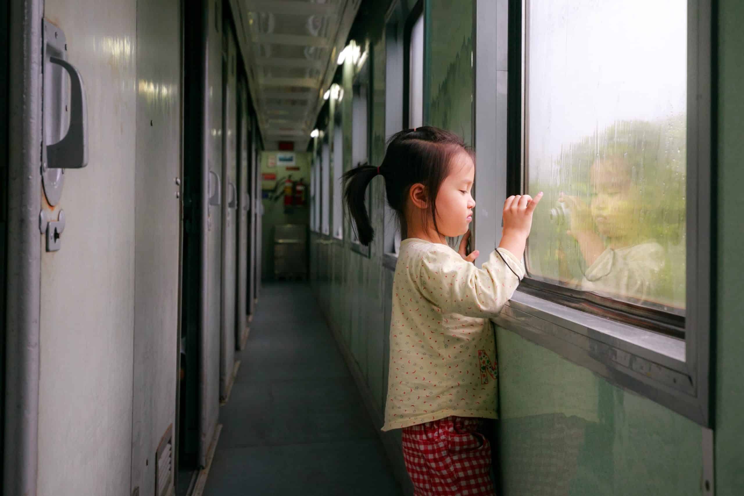 Little girl in a family train trips looking out of the train window