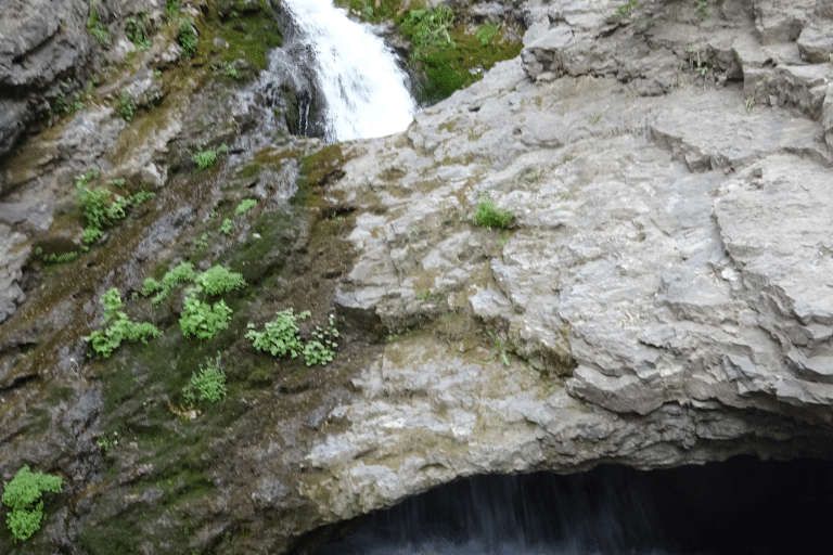 Water flowing through a donut shape rock formation in Donut Fall utah