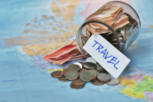 a world map with money from a budget jar spilled over with a stickers saying "travel"